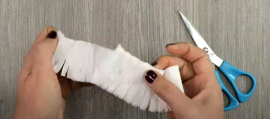 A person cutting a piece of paper with scissors Description automatically generated with low confidence